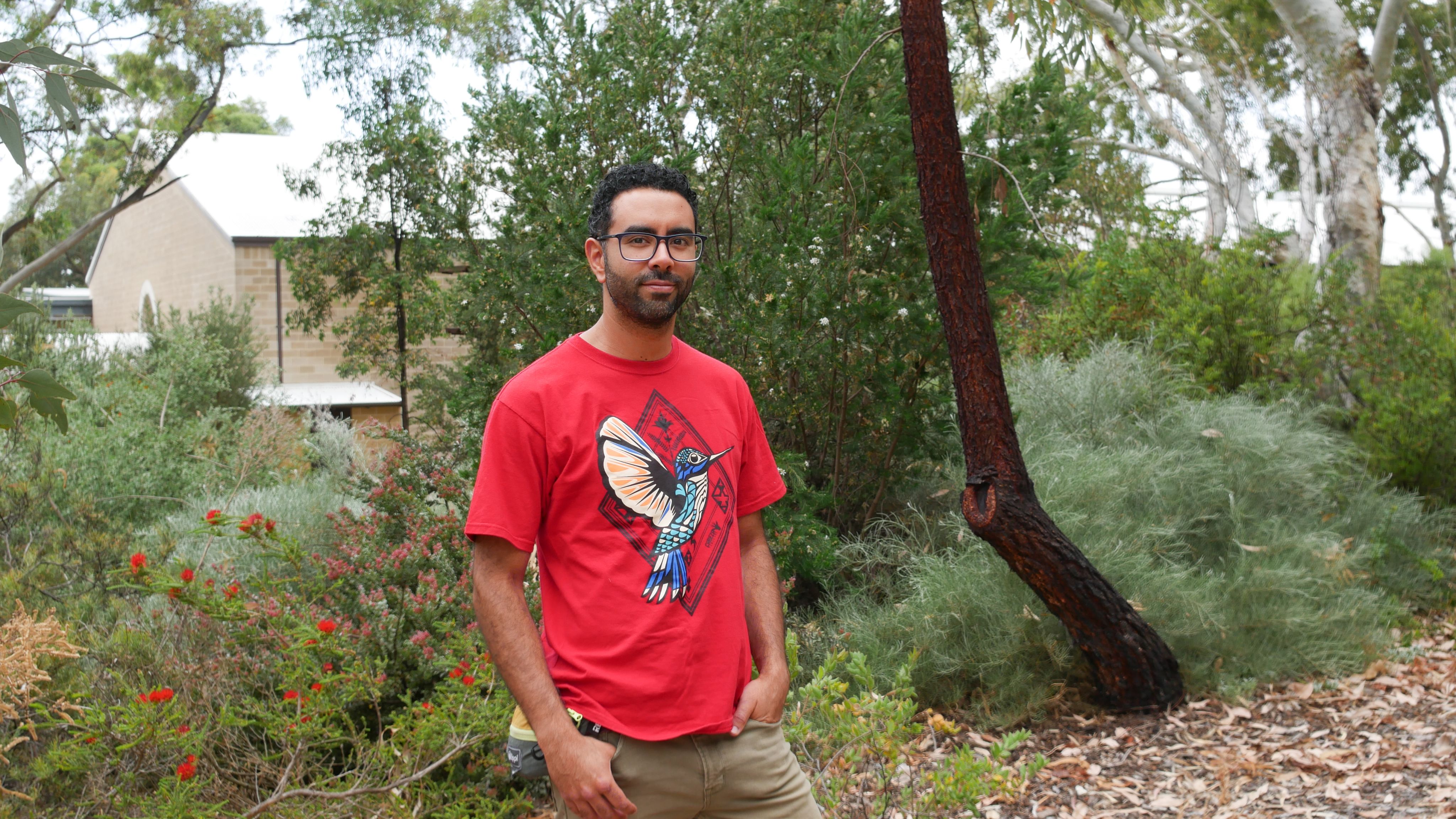 Nicolas Farias Rabelo standing in front of garden.