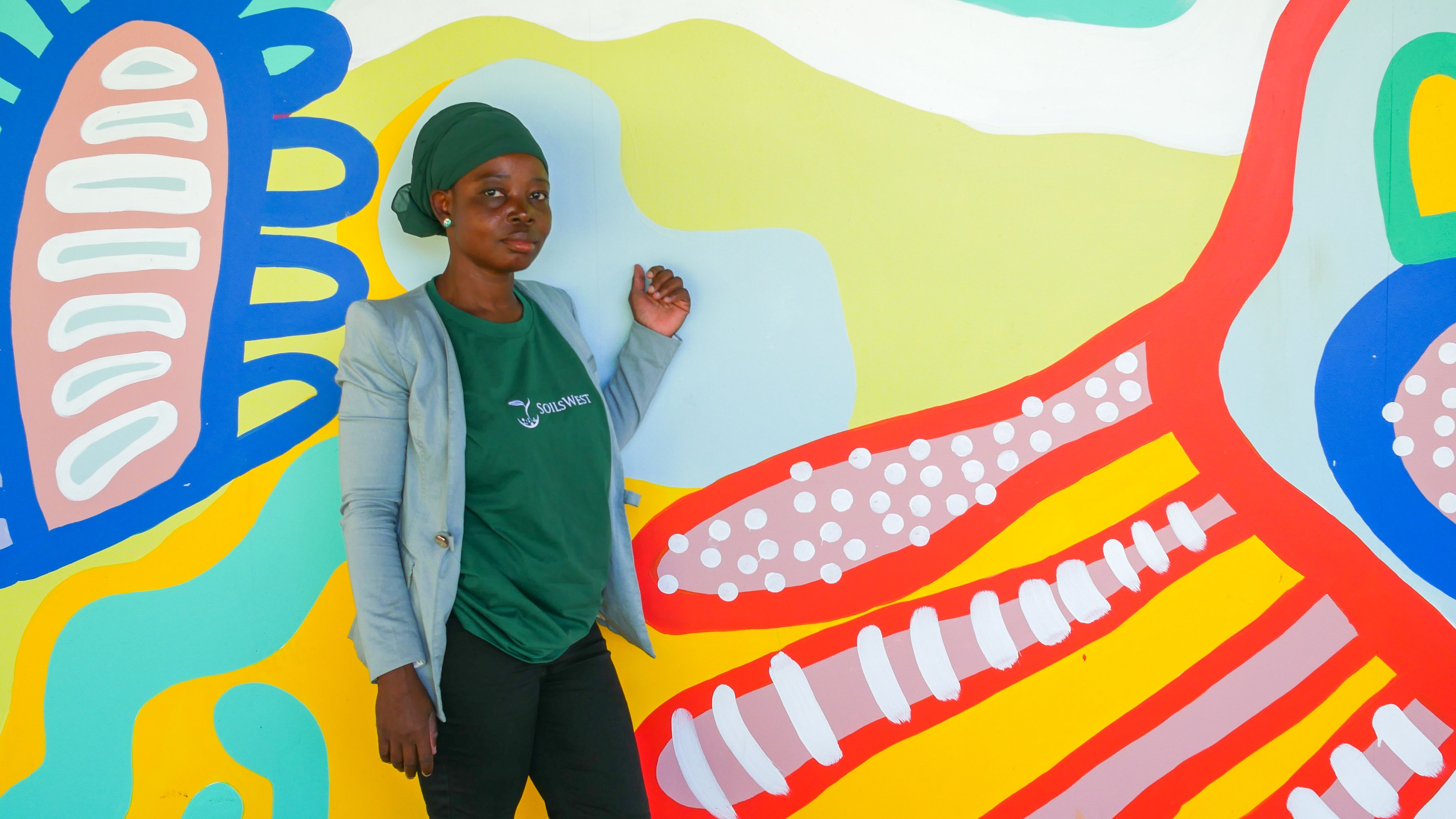 Fariya Abubakari standing in front of mural art wall.